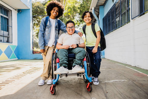 Two boys smiling alongside their friend in a wheelchair at school